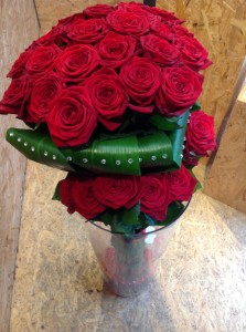 mazzo di rose rosse disposte a scettro con rose su due livelli e finitura con foglie di aspidstria e strass brillanti adesivi